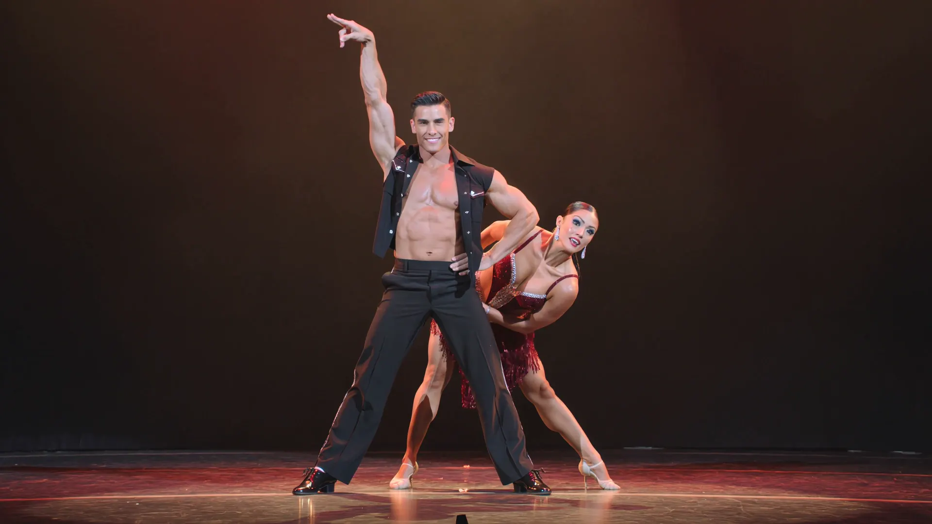 A dancer mid-movement in a dark studio, lit from behind