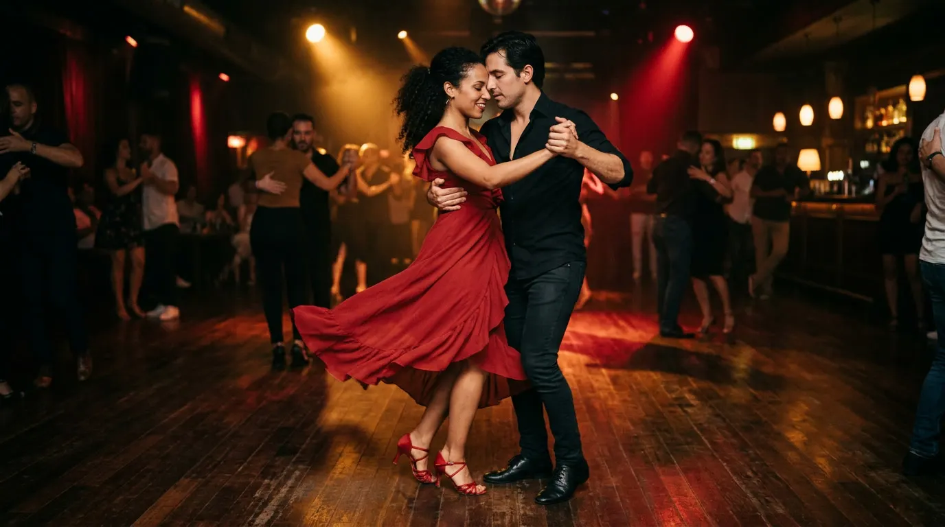A couple dancing bachata in a dimly lit hall